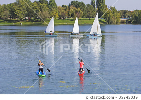 Two women on paddle board and three boat sailling 35245039