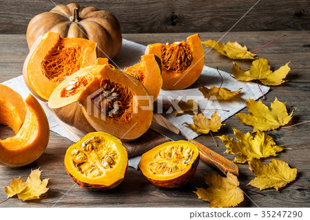 Sliced pumpkin with seeds on a wooden background Sliced pumpkin with seeds on a wooden background 35247290
