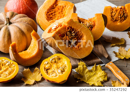 Sliced pumpkin with seeds on a wooden background Sliced pumpkin with seeds on a wooden background 35247292