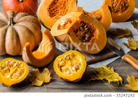 Sliced pumpkin with seeds on a wooden background Sliced pumpkin with seeds on a wooden background 35247293