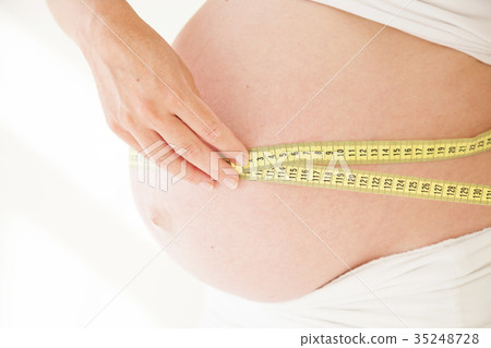 the stomach of a pregnant woman and a measuring the stomach of a pregnant woman and a measuring 35248728