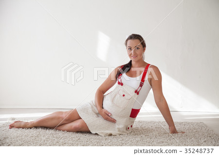 a pregnant woman sitting on the floor talking with a pregnant woman sitting on the floor talking with 35248737