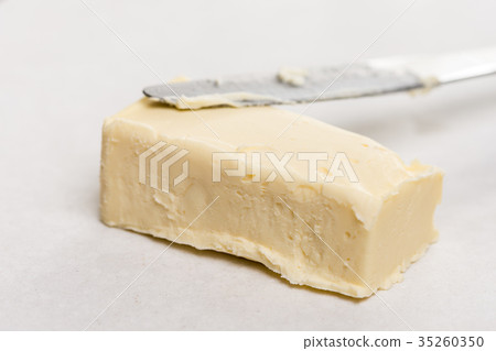 Slice of butter on the paper on white marble table Slice of butter on the paper on white marble table 35260350