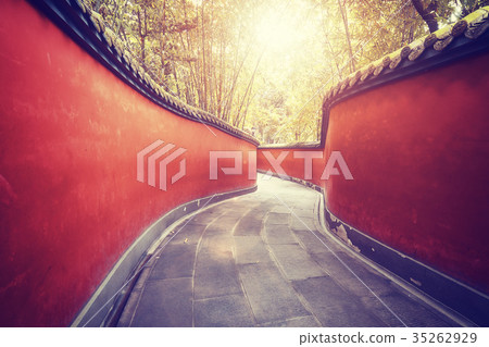 Curvy red walls passage surrounded by bamboos. Curvy red walls passage surrounded by bamboos. 35262929