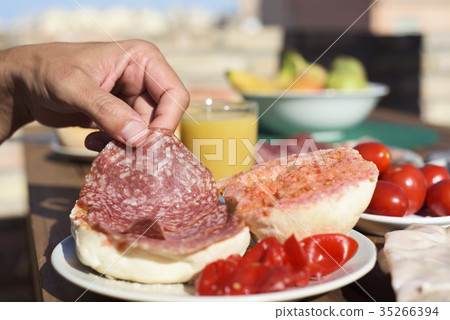 man preparing a salami sandwich 35266394