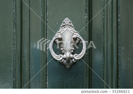 Vintage antiqued door knocker on wooden green door 35266821