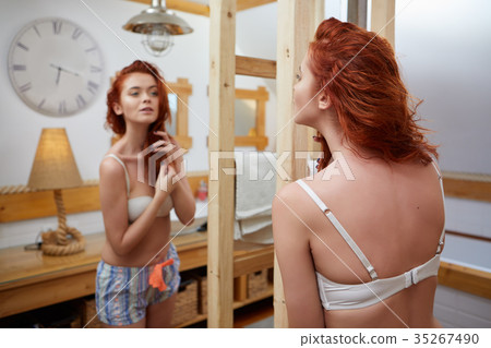 Young woman brushing healthy hair in front of a mirror 35267490