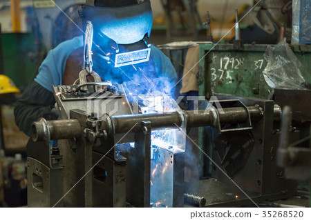 Man is welding an automotive part. 35268520