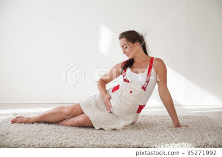 a pregnant woman sitting on the floor talking with 35271992