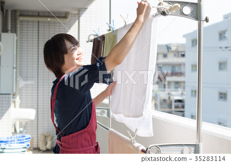 A woman who hangs laundry on the balcony A woman who hangs laundry on the balcony 35283114