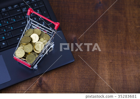 Shopping trolley with coins on a laptop Shopping trolley with coins on a laptop 35283681
