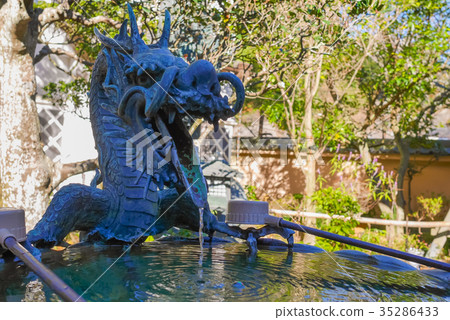 A scene of worshippers praying at a dragon-shaped water basin and ladle within the grounds of a temple in Kamakura. A scene of worshippers praying at a dragon-shaped water basin and ladle within the grounds of a temple in Kamakura. 35286433
