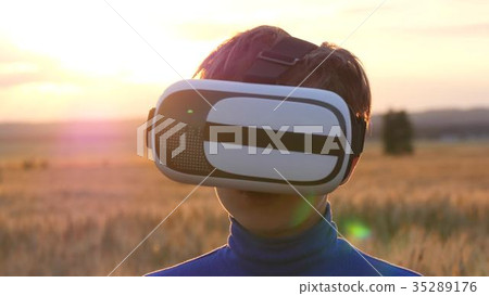 A boy stands in a wheat field at sunset in virtual A boy stands in a wheat field at sunset in virtual 35289176