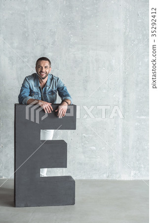 Joyful stylish bristled male is leaning on symbol Joyful stylish bristled male is leaning on symbol 35292412