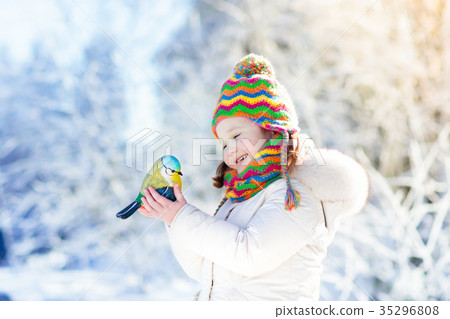 Child feed bird in winter park. Kids play in snow. Child feed bird in winter park. Kids play in snow. 35296808