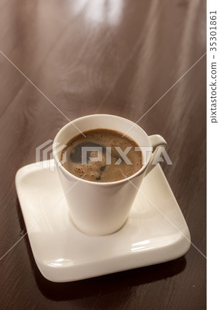White cup of coffee on the brown wooden table White cup of coffee on the brown wooden table 35301861