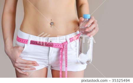 Close-up of female belly with measuring tape 35325494