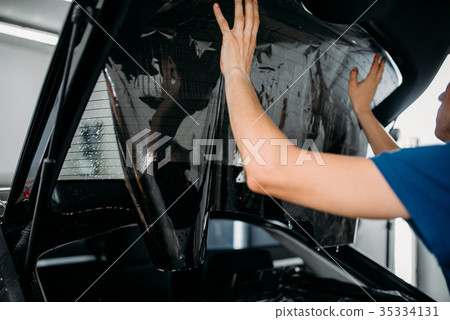 Male worker applying car tinting film 35334131
