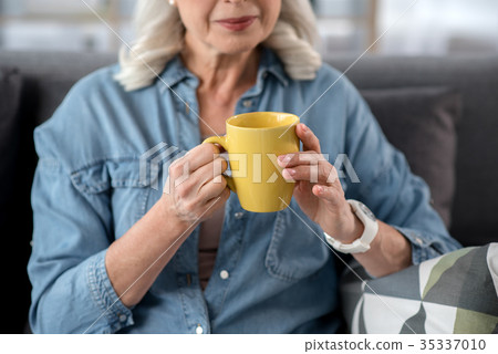 Cheerful mature lady drinking mu of beverage 35337010