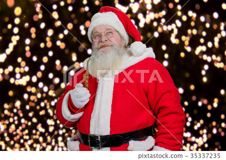 Santa with pipe on New Year lights background. 35337235
