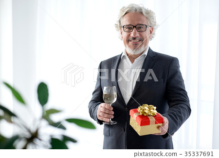 Cheerful senior businessman standing with present 35337691