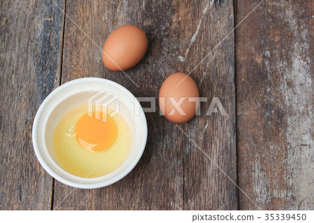 Raw egg in a bowl  on wooden table, Top view  35339450