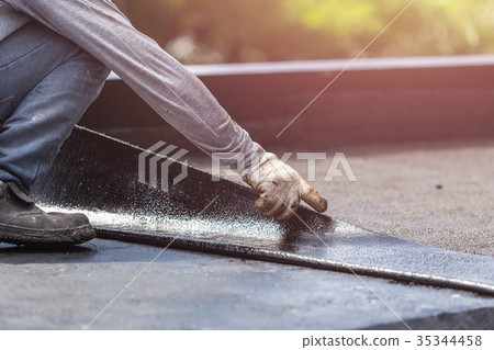 Group of worker installing tar foil on the rooftop of building. Waterproof system by gas and fire torching Group of worker installing tar foil on the rooftop of building. Waterproof system by gas and fire torching 35344458