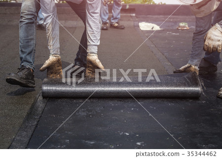 Group of worker installing tar foil on the rooftop of building. Waterproof system by gas and fire torching Group of worker installing tar foil on the rooftop of building. Waterproof system by gas and fire torching 35344462