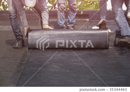 Group of worker installing tar foil on the rooftop of building. Waterproof system by gas and fire torching Group of worker installing tar foil on the rooftop of building. Waterproof system by gas and fire torching 35344463