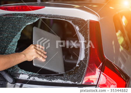 Hand stealing laptop from back side of car which rear glass broken 35344882