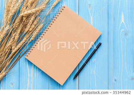 Dried wheat crop and blank of book for text or design on blue wooden board 35344962
