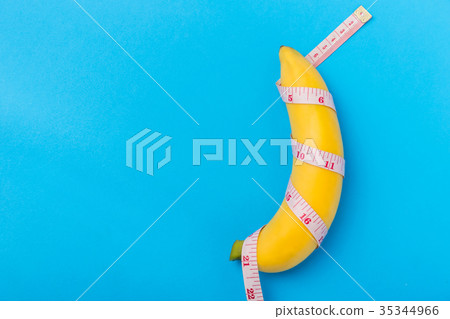 Yellow banana with measurement tape on blue background. Men penis size concept with empty free space for text or design. Top view Yellow banana with measurement tape on blue background. Men penis size concept with empty free space for text or design. Top view 35344966