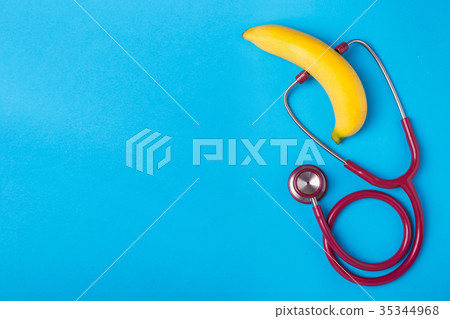 Stethoscope and yellow banana on blue background. For men penis check up concept. With empty free space for text or design. Top view 35344968