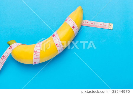 Yellow banana with measurement tape on blue background. Men penis size concept with empty free space for text or design. Top view 35344970