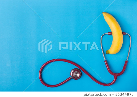 Stethoscope and yellow banana on blue background. For men penis check up concept. With empty free space for text or design. Top view 35344973