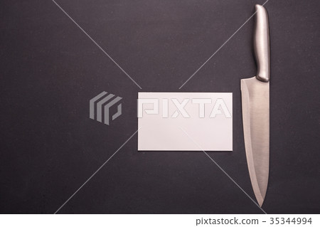 Stainless steel cooking knife on black stone background. Top view with free space and paper note for text or design Stainless steel cooking knife on black stone background. Top view with free space and paper note for text or design 35344994