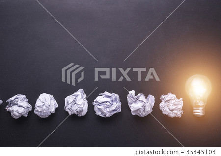 Top view crumpled paper and light bulbs on black stone board. Create idea concept Top view crumpled paper and light bulbs on black stone board. Create idea concept 35345103