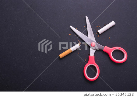 Stop smoking concept. Pink scissor cut cigarette in meaning STOP. Top view on black board 35345128
