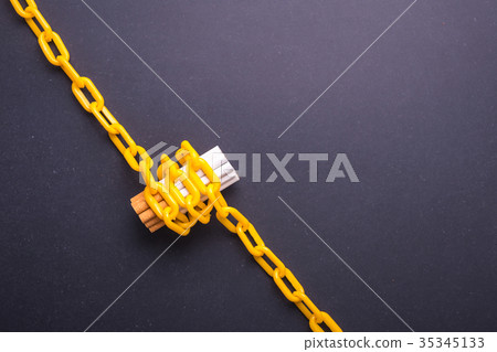 Stop smoking concept. Yellow chain locked around cigarette. Top view on black board Stop smoking concept. Yellow chain locked around cigarette. Top view on black board 35345133