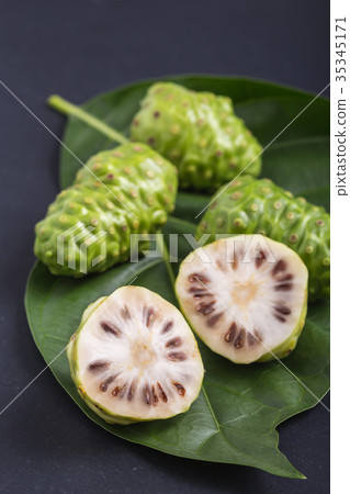 Fruit of Great morinda (Noni) or Morinda citrifolia tree and green leaf on black stone board Fruit of Great morinda (Noni) or Morinda citrifolia tree and green leaf on black stone board 35345171