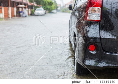 Car parking on the street of village while raining and show level of water flooding Car parking on the street of village while raining and show level of water flooding 35345310