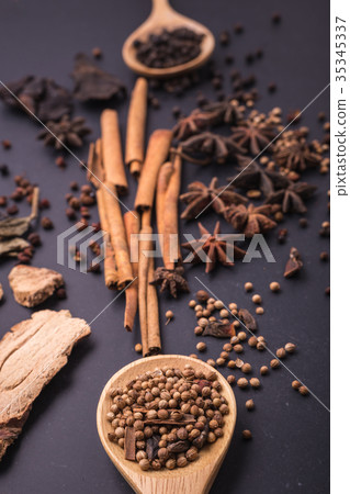 Mix of dried spices and herb on black stone table 35345337