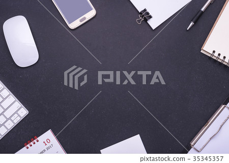 Office equipment, mouse, keyboard, smartphone, blank paper note, pen and calendar on black stone table. Middle free space for text or design Office equipment, mouse, keyboard, smartphone, blank paper note, pen and calendar on black stone table. Middle free space for text or design 35345357