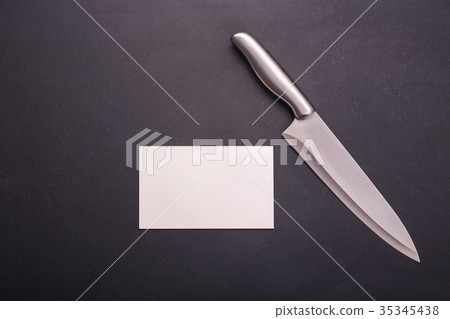 Stainless steel cooking knife on black stone background. Top view with free space and paper note for text or design 35345438