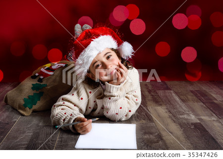 Adorable little girl wearing santa hat writing Santa letter Adorable little girl wearing santa hat writing Santa letter 35347426