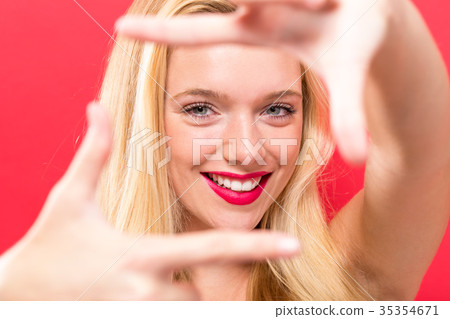 Young woman framing her face with her fingers Young woman framing her face with her fingers 35354671