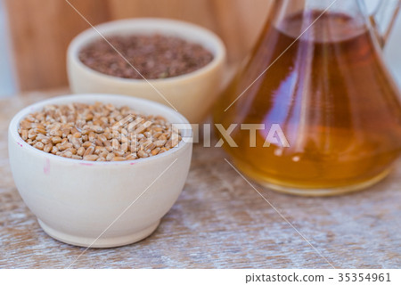 Wheat grains in wooden bowl and oil in decanter Wheat grains in wooden bowl and oil in decanter 35354961