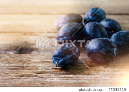 Blue organic plums on dark wooden background Blue organic plums on dark wooden background 35356219