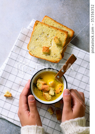 Cup with carrot cream soup in girl hands on light Cup with carrot cream soup in girl hands on light 35356352