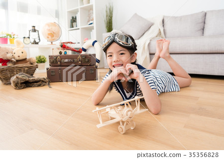 happy girl as pilot playing with wooden airplane 35356828